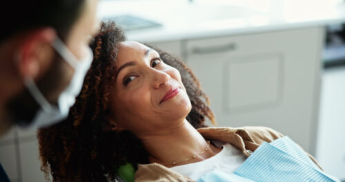 A woman sits in a dental chair while dentist talks about appointment